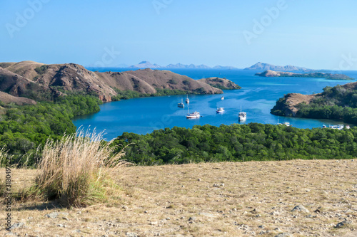 A view from top of the Komodo Island in Indonesia. Discovering new places. There is a lot of boats anchored to the shores of the island's bay. Other islands in the back. Volcanic island. photo