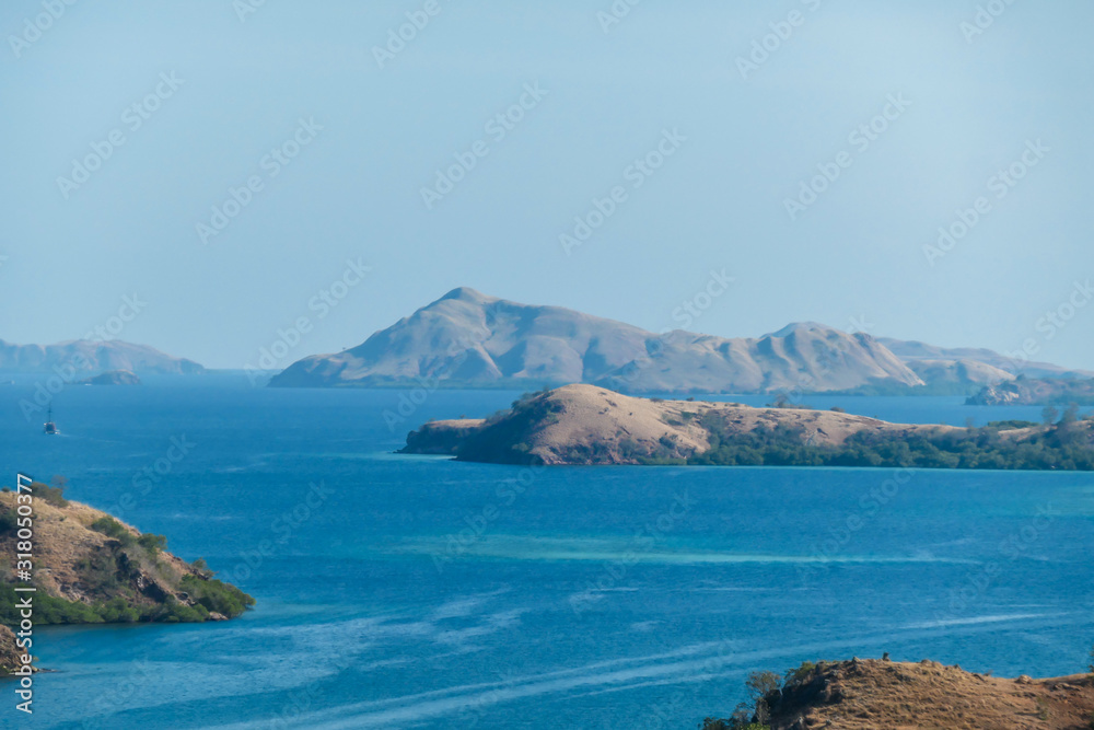 Idyllic island formation seen from Komodo Island in Indonesia. Discovering new places. Calm sea gently washes the shores of the islands. Volcanic islands with barely any plants.