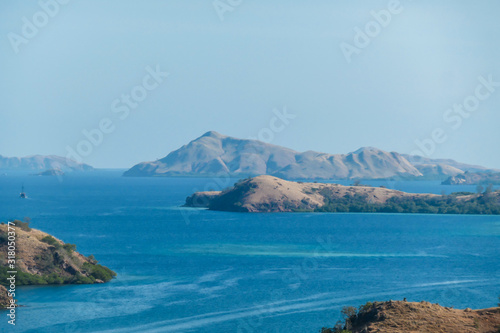 Idyllic island formation seen from Komodo Island in Indonesia. Discovering new places. Calm sea gently washes the shores of the islands. Volcanic islands with barely any plants. photo