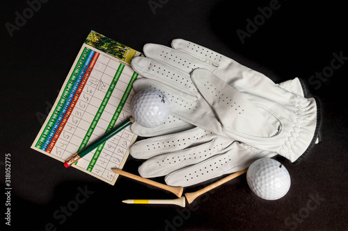 Slika na platnu Golf ball tee’s in front of golf balls and gloves illustrative photo shot on black studio background isolated recreational sport equipment for golf courses and leisure, hobbies and retirement