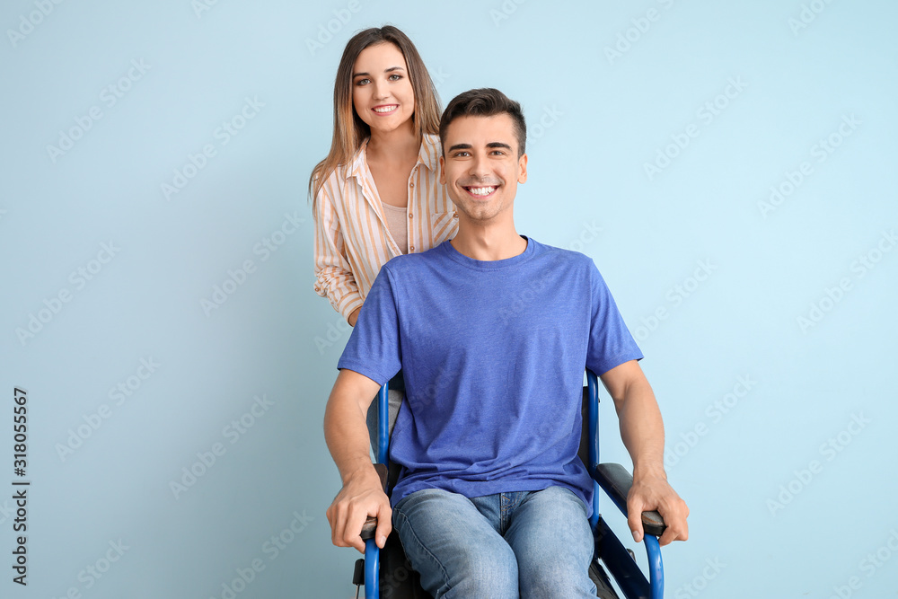 Handicapped young man in wheelchair and his wife on color background Handicapped young man in wheelchair and his wife on color background