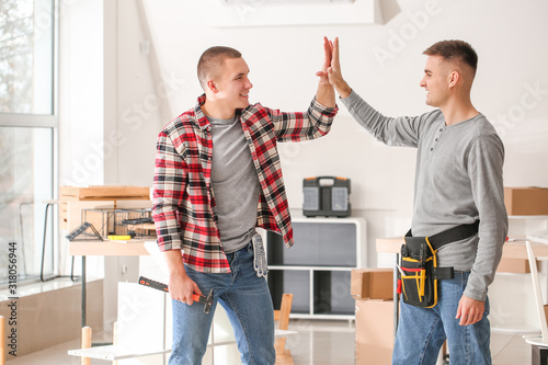 Furniture assemblers giving high-five to each other in workshop photo