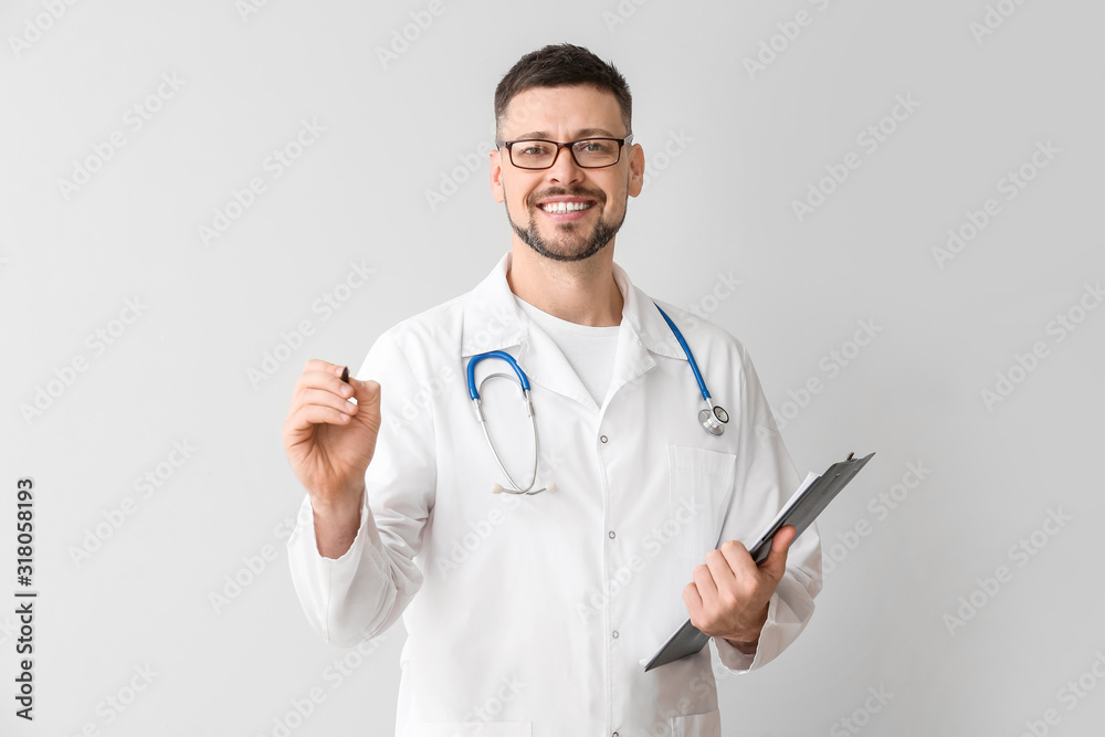 Male cardiologist writing on virtual screen against light background Male cardiologist writing on virtual screen against light background