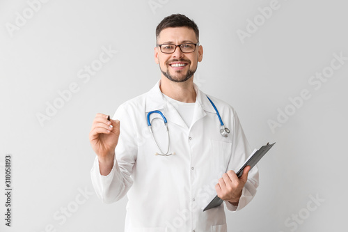 Male cardiologist writing on virtual screen against light background