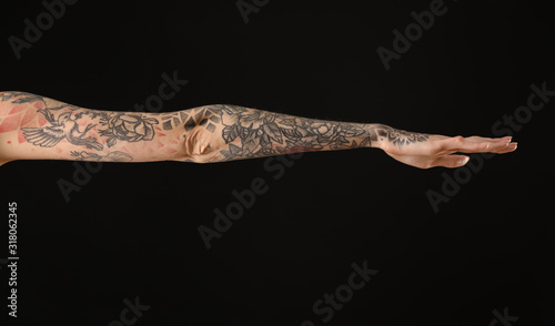 Woman with colorful tattoos on arm against black background, closeup