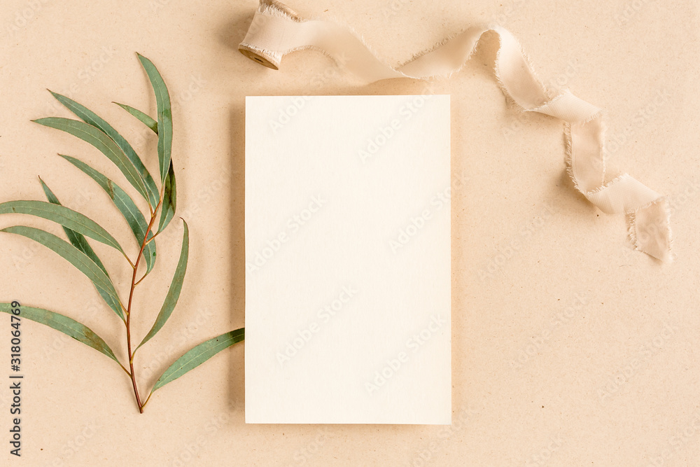 Fototapeta premium Mockup invitation, blank greeting card and green leaves eucalyptus. Flat lay, top view.