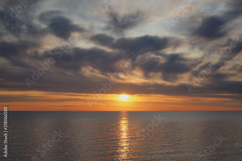 Golden sunset with lots of clouds above water horizon. © Maxim