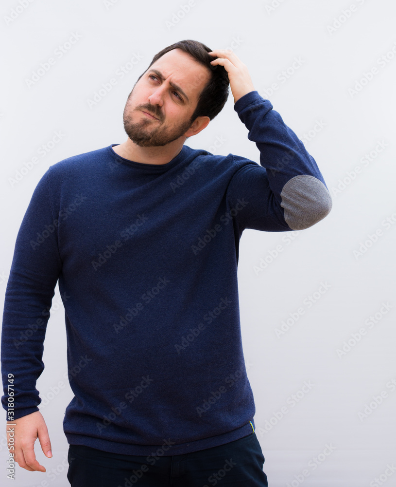 young handsome man feeling puzzled and confused, scratching head and looking to the side agains.