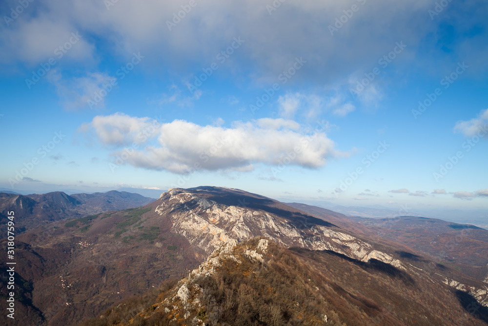 Beautiful rocky mountain peak, forests colored with late autumn colors and blue sky with soft clouds over Vlaska planina in Serbia, near village Vlasi