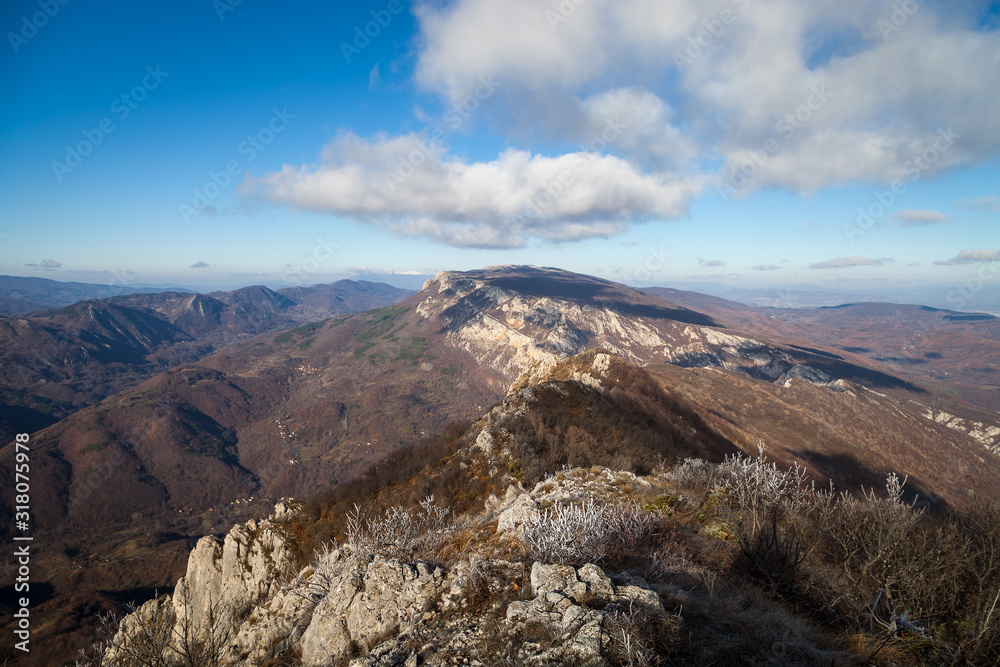 Beautiful rocky mountain peak, forests colored with late autumn colors and blue sky with soft clouds over Vlaska planina in Serbia, near village Vlasi