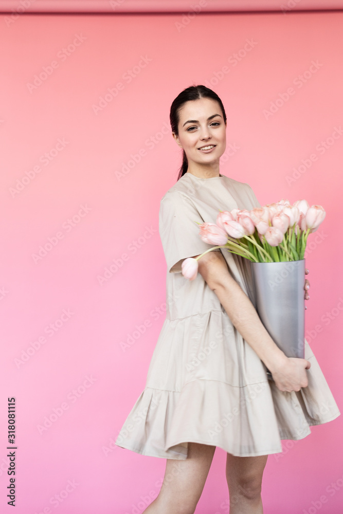 Girl in a dress with a bouqet of flowers chamomile on a pink background in front of camera Girl in a dress with a bouqet of flowers chamomile on a pink background in front of camera