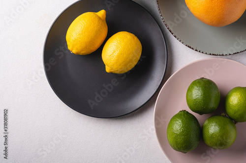 Lime, lemon, grapefruit in colorful plates on white background, angle view, vitamins and healthy food