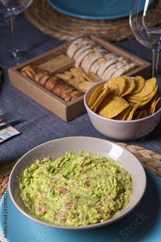 Green guacamole Mexican sauce food on a plate with bread toast slices close up still no a dark dinning table photo