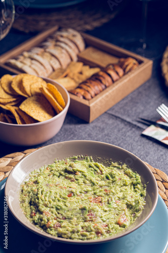 Green guacamole Mexican sauce food on a plate with bread toast slices close up still no a dark dinning table photo