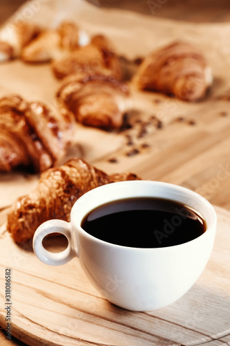 Cup of black freshly brewed coffee. Crispy croissant, breakfast in cafe.