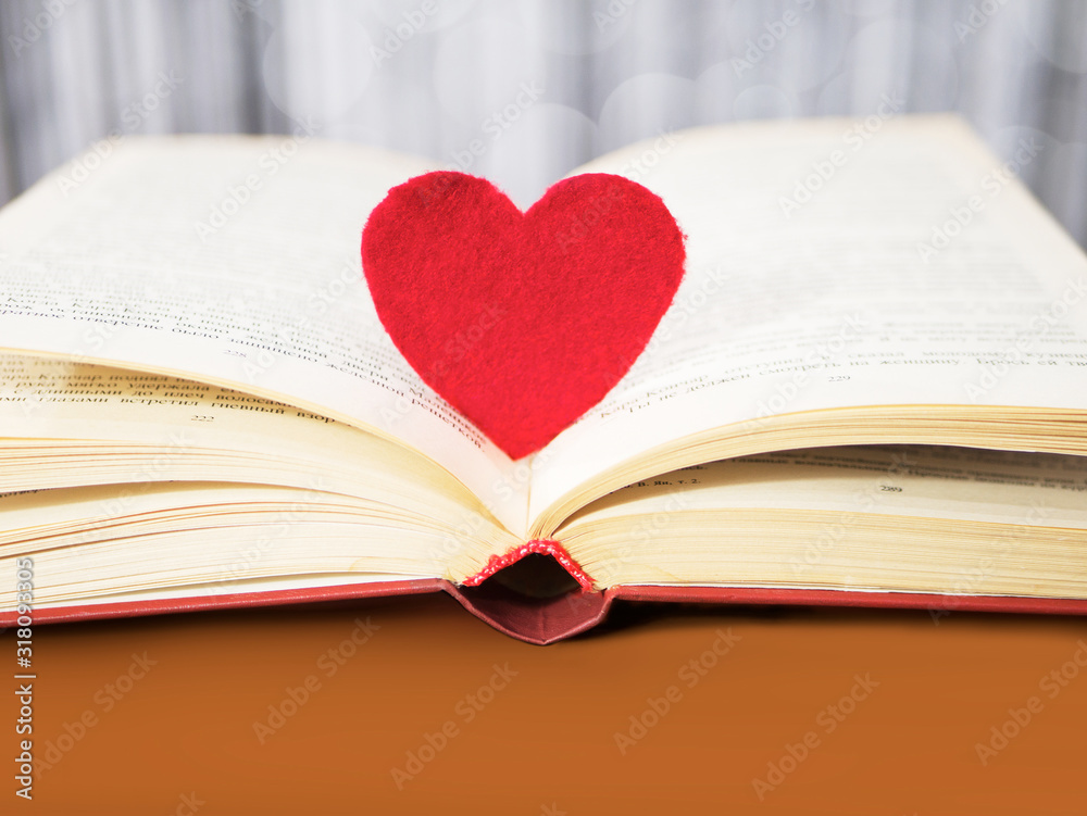 Red heart with old book concept. Greeting card for Valentine's day. Textile red heart for Valentines holiday. Romantic background and wallpaper Red heart with old book concept. Greeting card for Valentine's day. Textile red heart for Valentines holiday. Romantic background and wallpaper