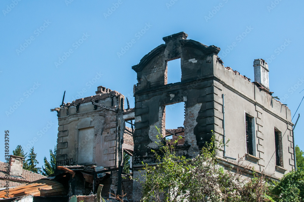 Old burnt and destroyed countryside house closeup in clear sunny day