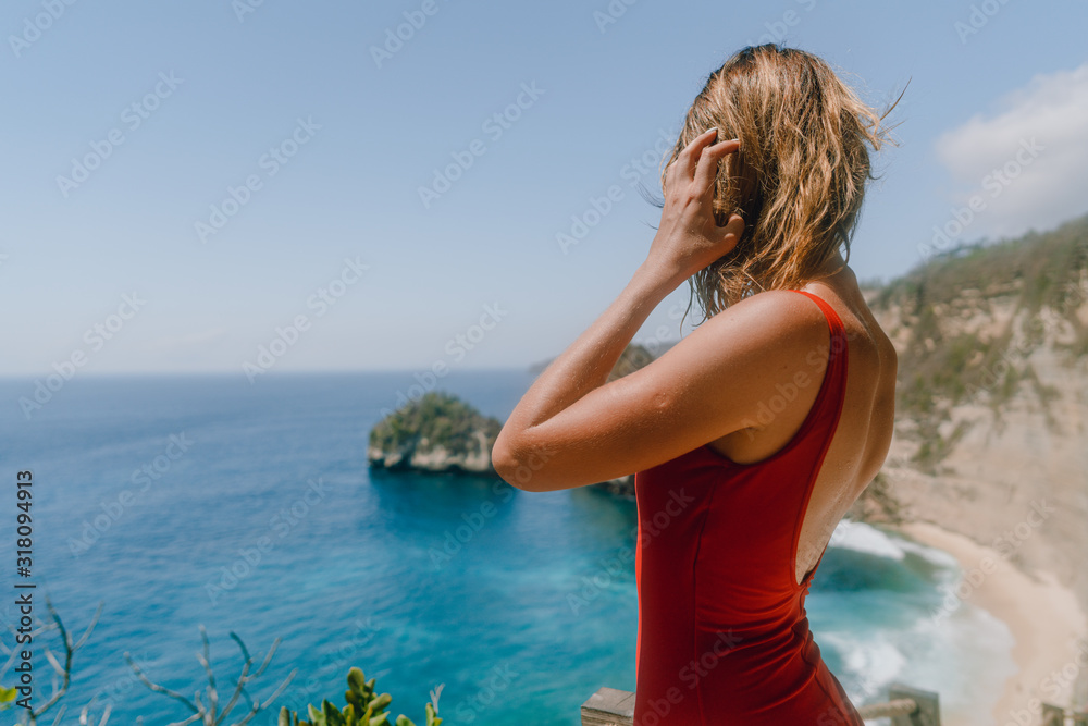 Close up of a young girl in the red swimsuit at the most beautiful Diamond Beach with azure water in Bali, Nusa Penida