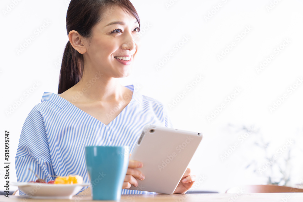 部屋でタブレットコンピューターを見る女性 部屋でタブレットコンピューターを見る女性