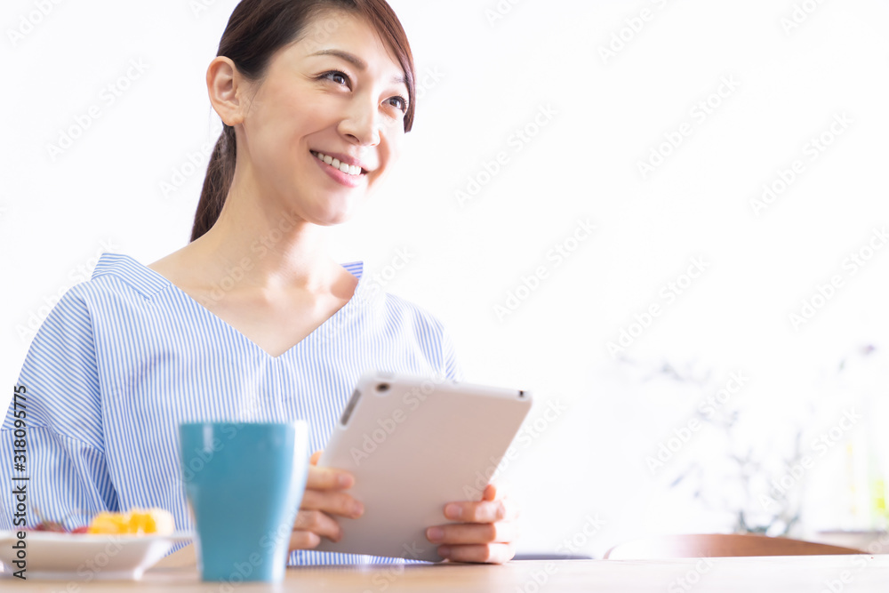 部屋でタブレットコンピューターを見る女性 部屋でタブレットコンピューターを見る女性