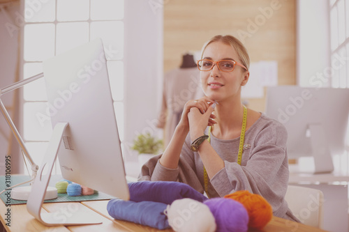 Fashion designer woman working in studio, sitting at thhe desk photo