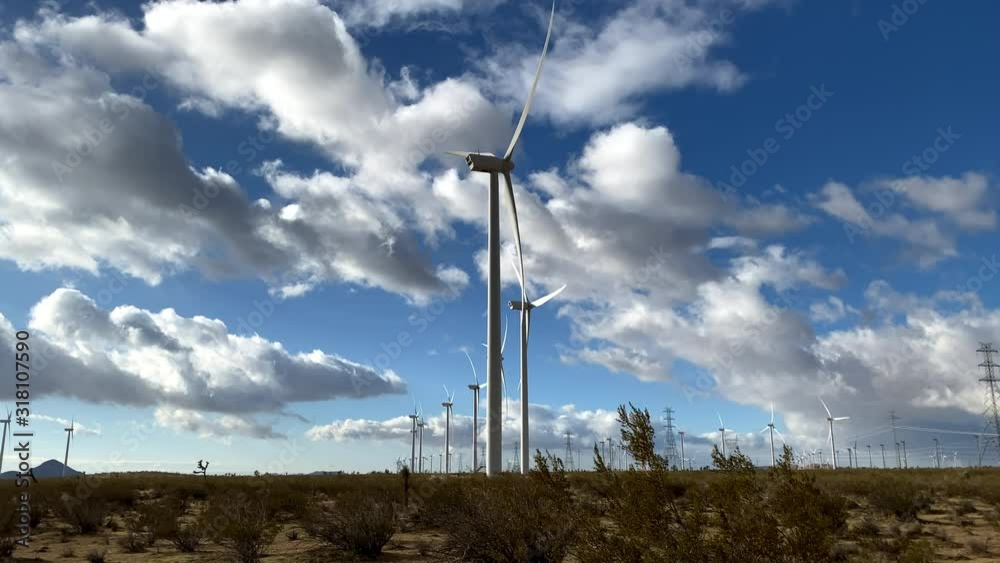 Driving past massive wind turbines with dramatic clouds in the background. Shot in the Mojave Desert in California. Driving past massive wind turbines with dramatic clouds in the background. Shot in the Mojave Desert in California.