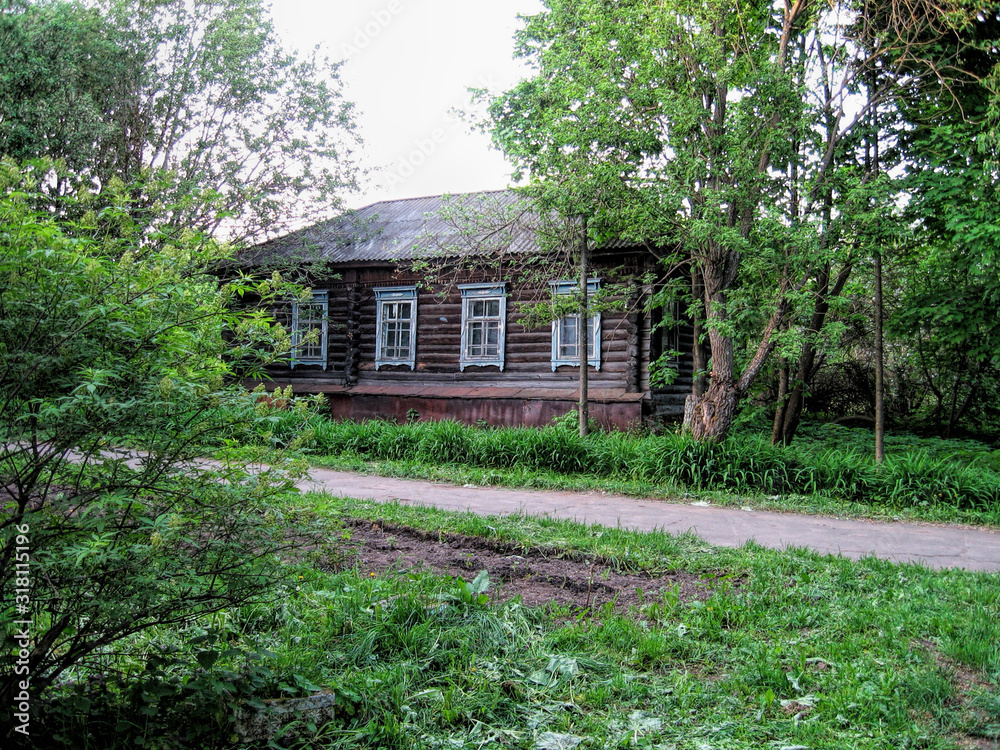 Road next to an old wooden house in summer in Russia Road next to an old wooden house in summer in Russia