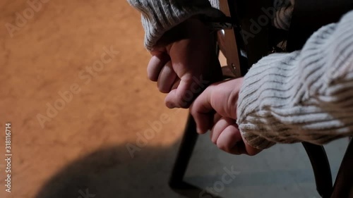 Hands of a man handcuffed to a chair trying to break free