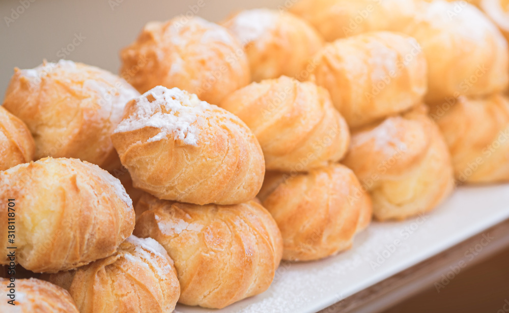 Close-up Cream puffs (Profiterole), a filled French choux pastry ball with vanilla custard and dusted with icing on top at the international buffet restaurant.