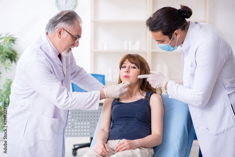 Obraz premium Two male doctors and young woman in plastic surgery concept