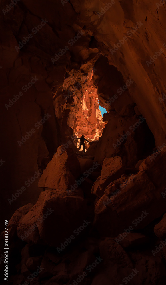 young man climbing down into large sandstone cavern