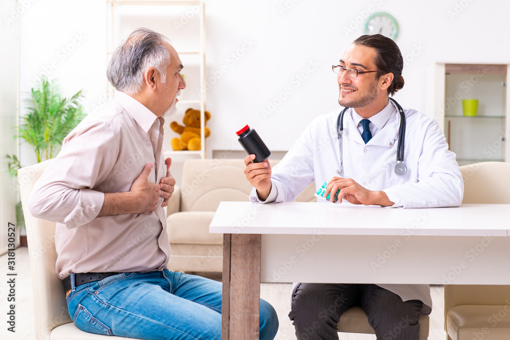 Obraz premium Young male doctor visiting old patient at home