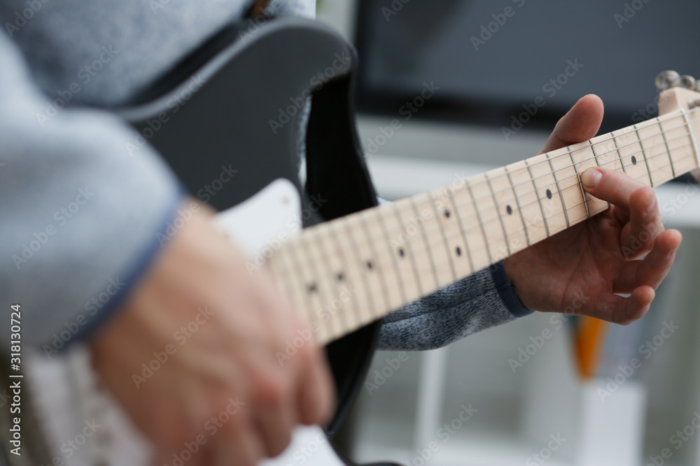 Male hands at home play and tune the electric guitar is engaged in music realizes listening enjoying music notation large concept closeup