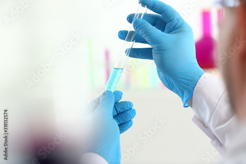 A male chemist holds test tube of glass in his hand overflows a liquid solution of potassium permanganate conducts an analysis reaction takes various versions of reagents using chemical manufacturing.