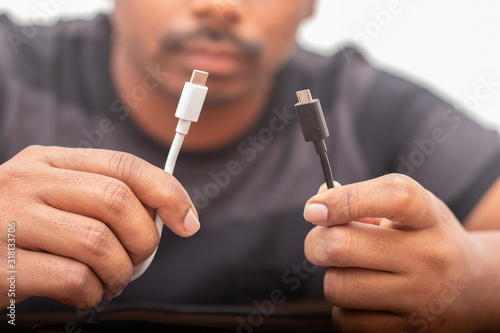 Selective focus on hands holding micro usb and USB type C ports concepts showing of confusion on charging ports.