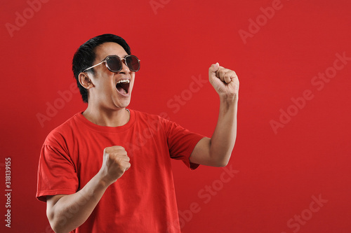 Young asian man happy and excited expressing winning gesture. Successful and celebrating