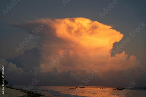 Big white clouds and sky over sea water on tropical beach during sunrise on the island of Zanzibar, Tanzania, Africa. Travel and nature concept