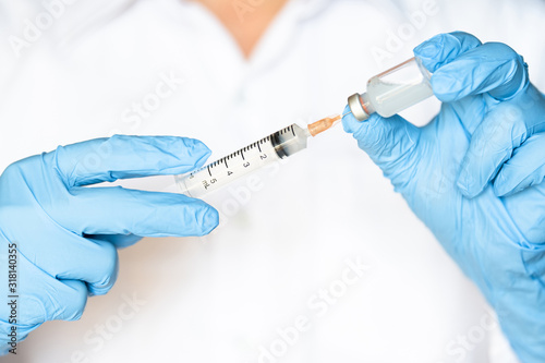 Doctor or nurse hand in blue gloves holding flu, measles vaccine shot for baby and adult vaccination, medicine and drug concept
