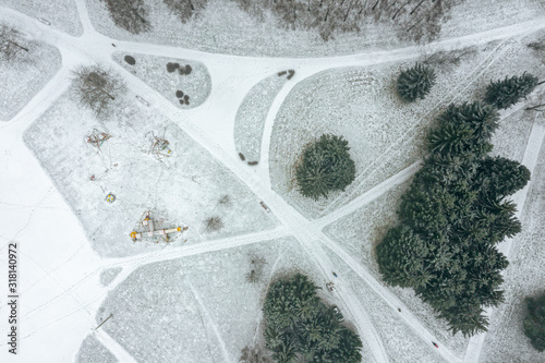 top view of city park walkway and trees covered with snow. aerial top down view