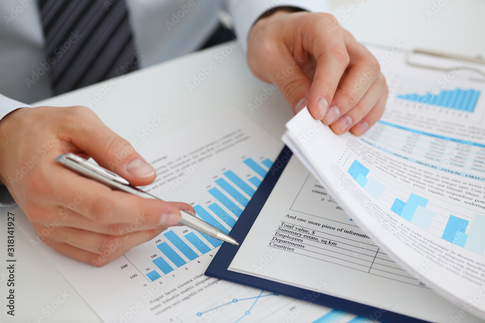 Male hands hold documents with financial statistics at office workspace closeup. White collar check money papers stock exchange market internal Revenue Service inspector earning list concept