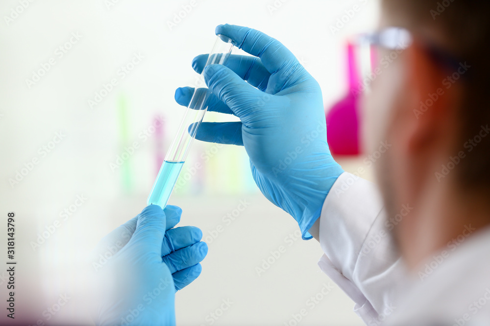 A male chemist holds test tube of glass in his hand overflows a liquid solution of potassium permanganate conducts an analysis reaction takes various versions of reagents using chemical manufacturing. A male chemist holds test tube of glass in his hand overflows a liquid solution of potassium permanganate conducts an analysis reaction takes various versions of reagents using chemical manufacturing.