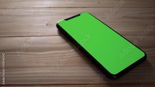 Smart phone place on table wood , Green screen telephone, Zoom shoulder view.