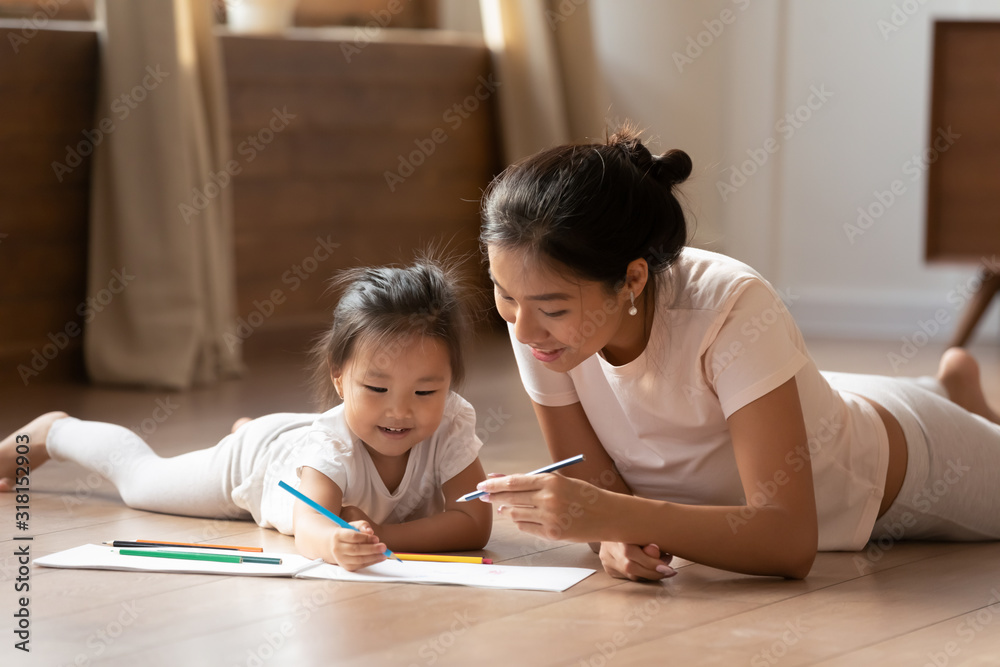 Young Asian mother and little daughter drawing together Young Asian mother and little daughter drawing together