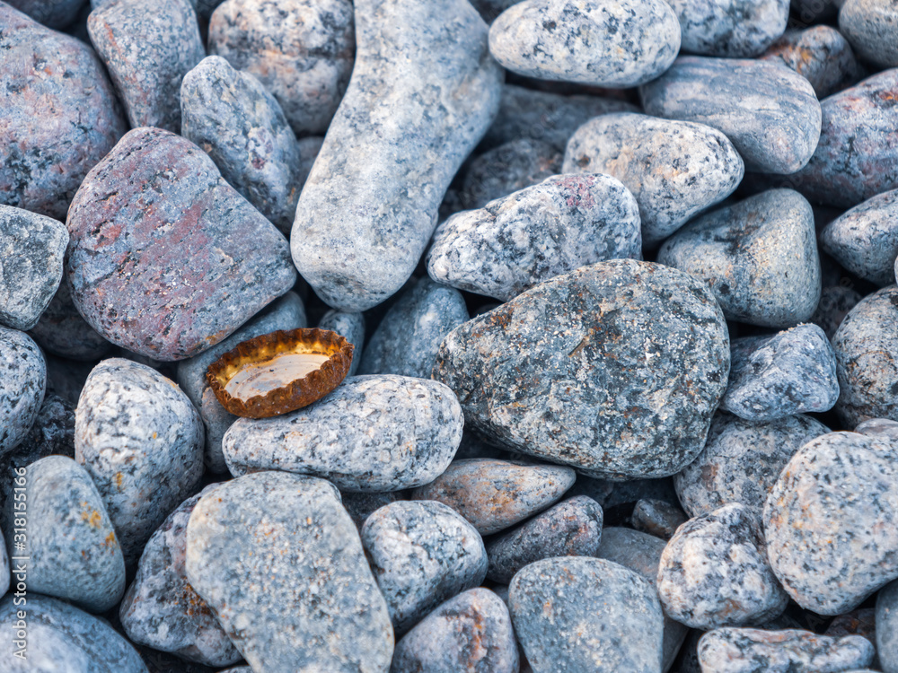 Rusty bottle cap lying on the sea pebbles. Ecology. Rocks on the shore of the Black sea. Rusty bottle cap lying on the sea pebbles. Ecology. Rocks on the shore of the Black sea.