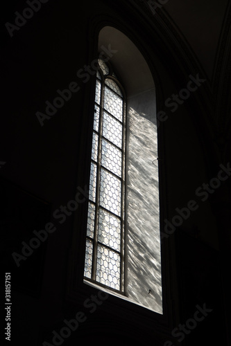 Side view of light through a Gothic stone church window among the dark background , copy space , wallpaper