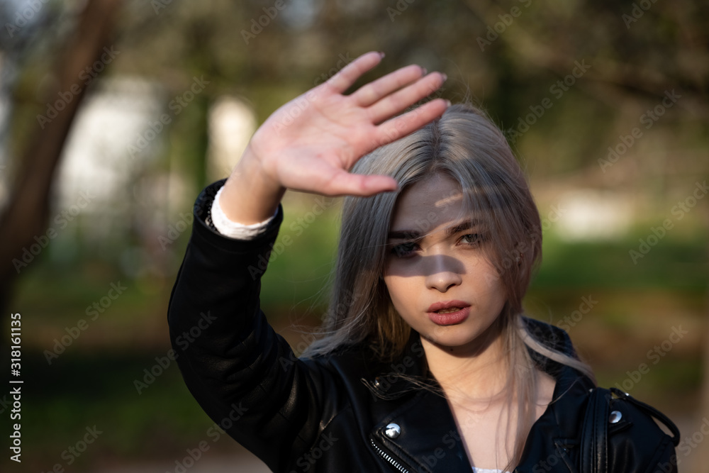 a beautiful young blonde girl holds her hand in front of her face hiding from the sun