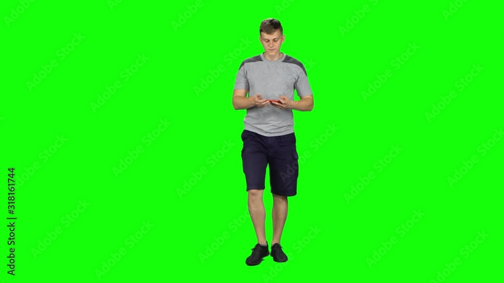 Smiling man goes and takes a selfie with smartphone on green screen at studio. Smiling man goes and takes a selfie with smartphone on green screen at studio.