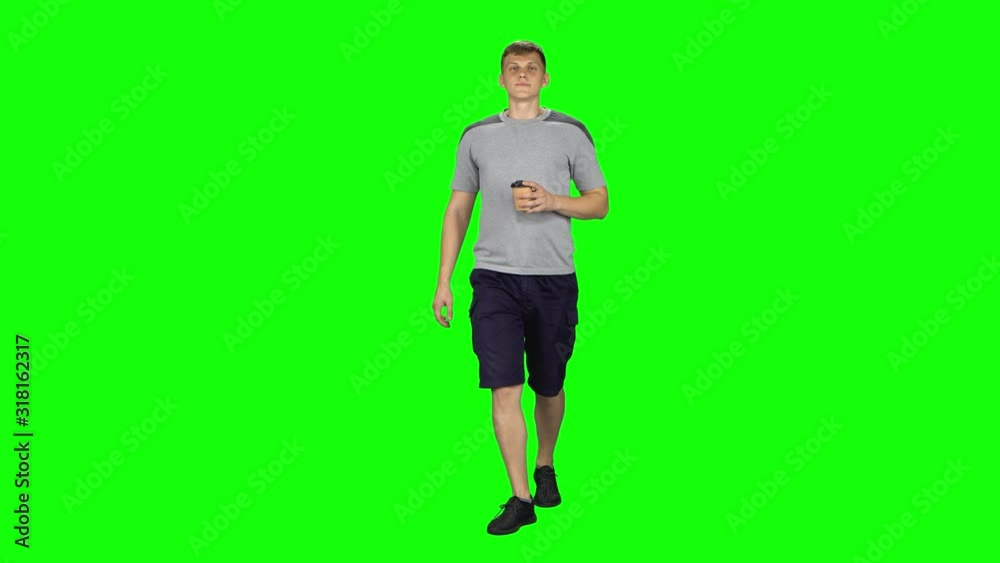 Young man walking and watching on the phone something, drinking coffee. Chroma Key Young man walking and watching on the phone something, drinking coffee. Chroma Key