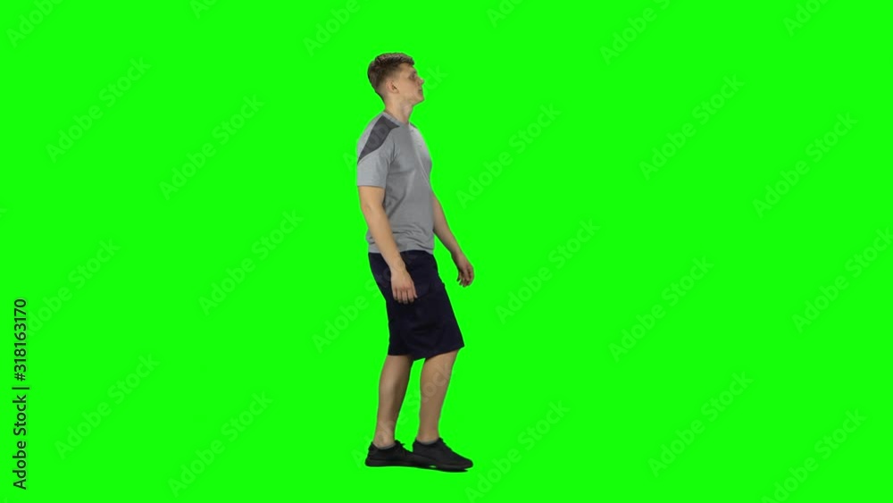 Young man walking on a Green Screen. Profile side view