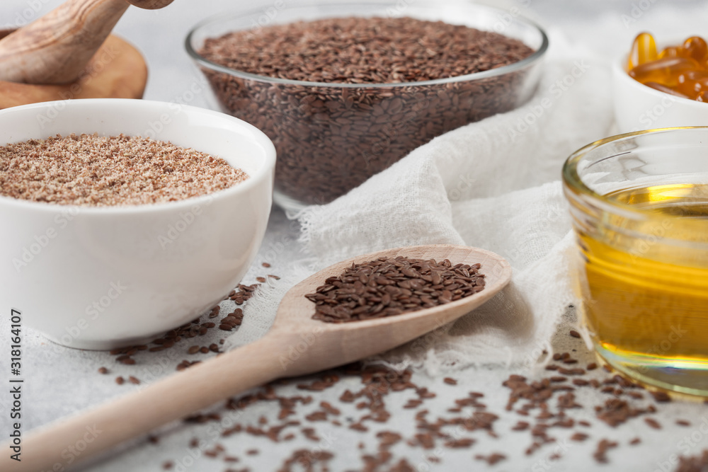 Bowl of raw natural organic linseed flax-seed with spoon and oil on light table background with linen cloth. Bowl of raw natural organic linseed flax-seed with spoon and oil on light table background with linen cloth.